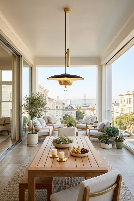 Adelaide Saucer Brass Pendant Light illuminating a modern dining area with glass walls and stylish furniture.