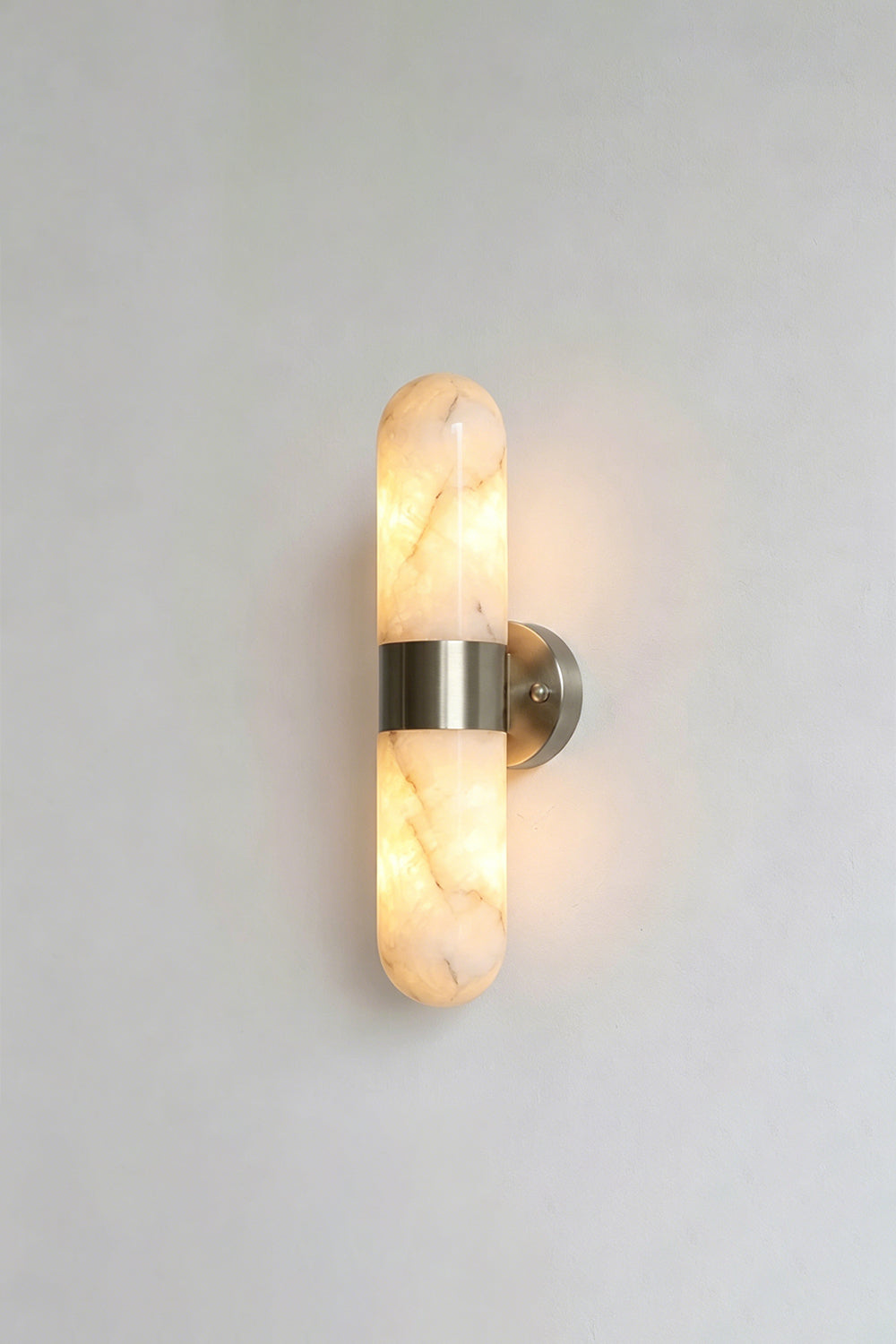 Calla Alabaster Capsule Wall Sconce | Alabaster, Metal | Another lit studio view of the polished chrome or silver nickel variant casting an elegant glow | vexa lamps