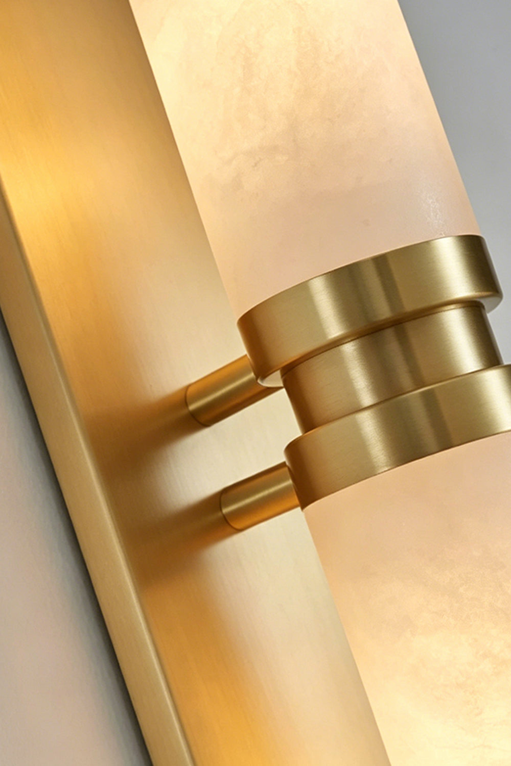 Linea Alabaster Capsule Wall Sconce | Alabaster, Brass | Close-up detail shot highlighting the textured alabaster stone cylinder and the central brushed brass bracket ring fixture | Detail shot | vexa lamps