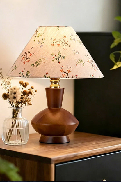 Arboreal Canopy Walnut Table Lamp on a wooden bedside table with a floral fabric shade and decorative vase.