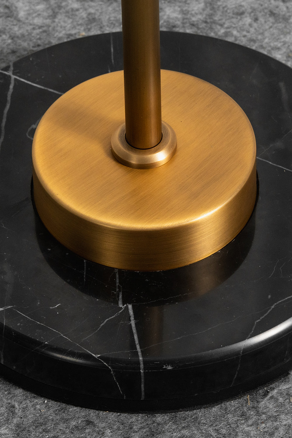 Aurelius Alabaster Brass Floor Lamp | Alabaster, Brass | Close-up structural view of the heavy circular brushed brass stem collar resting on the polished round black marble base plate with white veins | Detail shot | vexa lamps