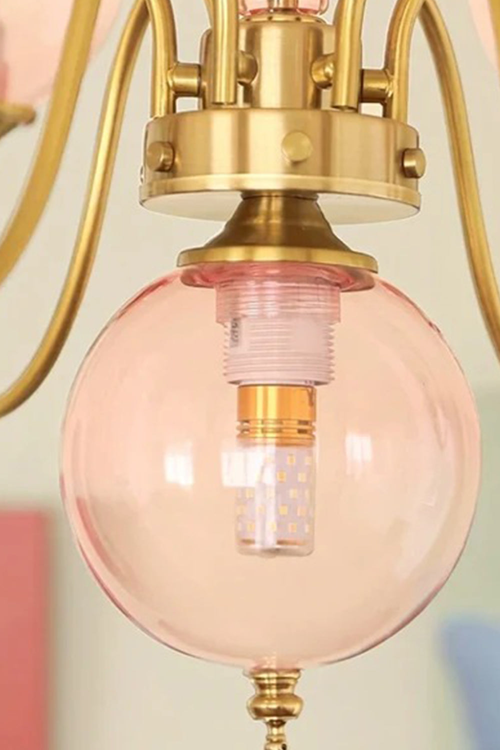 Aveline Globe Cluster Chandelier | Colored Glass and Brass | Close-up view of a single pink glass globe shade with brass fitting | vexa lamps