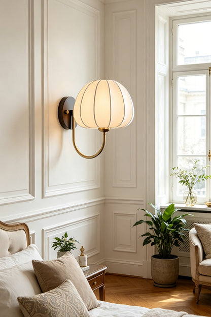 Baird Mid Century Pumpkin Wall Lamp | Metal, Fabric, Wood | Wall-mounted above a cozy lounge area with pillows and indoor plants in a classically decorated room | vexa lamps