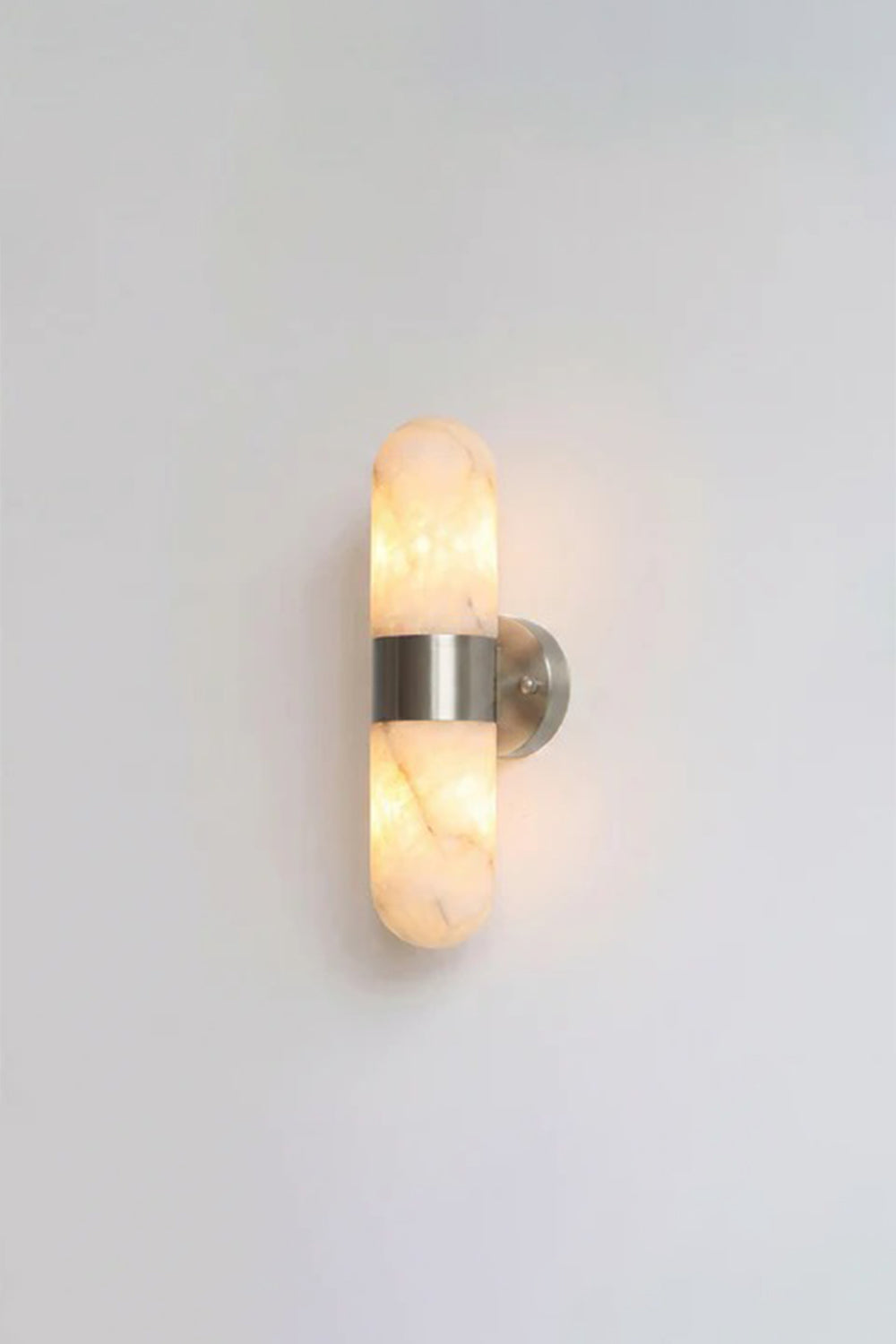 Calla Alabaster Capsule Wall Sconce | Alabaster, Metal | Fully lit studio presentation of the silver polished nickel variant on a clean light grey backdrop | vexa lamps