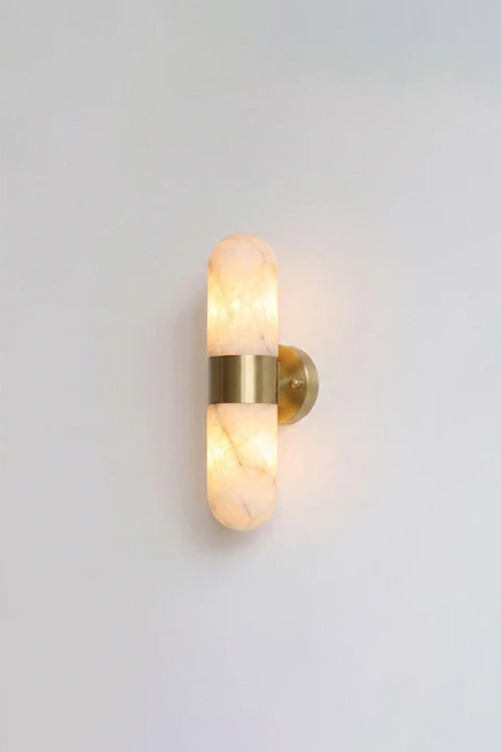 Calla Alabaster Capsule Wall Sconce | Alabaster, Brass | Fully lit studio view of the classic brushed gold brass hardware variant on a clean light grey backdrop | vexa lamps