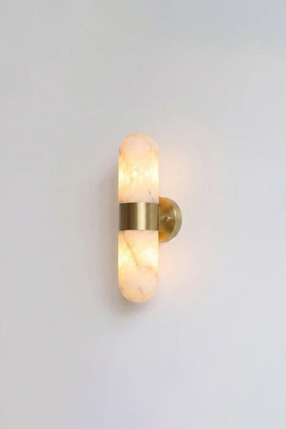 Calla Alabaster Capsule Wall Sconce | Alabaster, Brass | Fully lit studio view of the classic brushed gold brass hardware variant on a clean light grey backdrop | vexa lamps