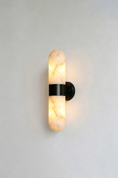 Calla Alabaster Capsule Wall Sconce | Alabaster, Metal | Lit studio view of the industrial modern matte black hardware finish variant against a white studio background | vexa lamps