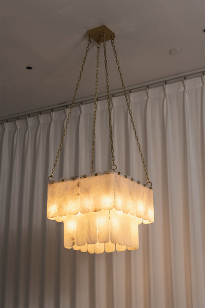 Callista Tiered Alabaster Chandelier | Alabaster, Metal | Studio centered view of the fully lit square tiered alabaster chandelier casting a beautiful warm architectural light against curtains | vexa lamps