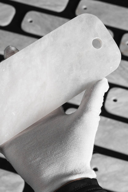 Callista Tiered Alabaster Chandelier | Alabaster, Metal | A gloved hand holding up a single polished rectangular white alabaster stone component to demonstrate its opacity and fine texture | Detail shot | vexa lamps