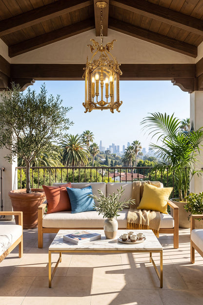 Corwin Glazed Brass Pendant Light hanging above a stylish outdoor seating area with lush greenery and city view.