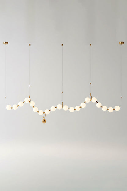 Delphine Pearl Strand Chandelier showcasing matte-white globes in a brass-toned design, perfect for elegant lighting.