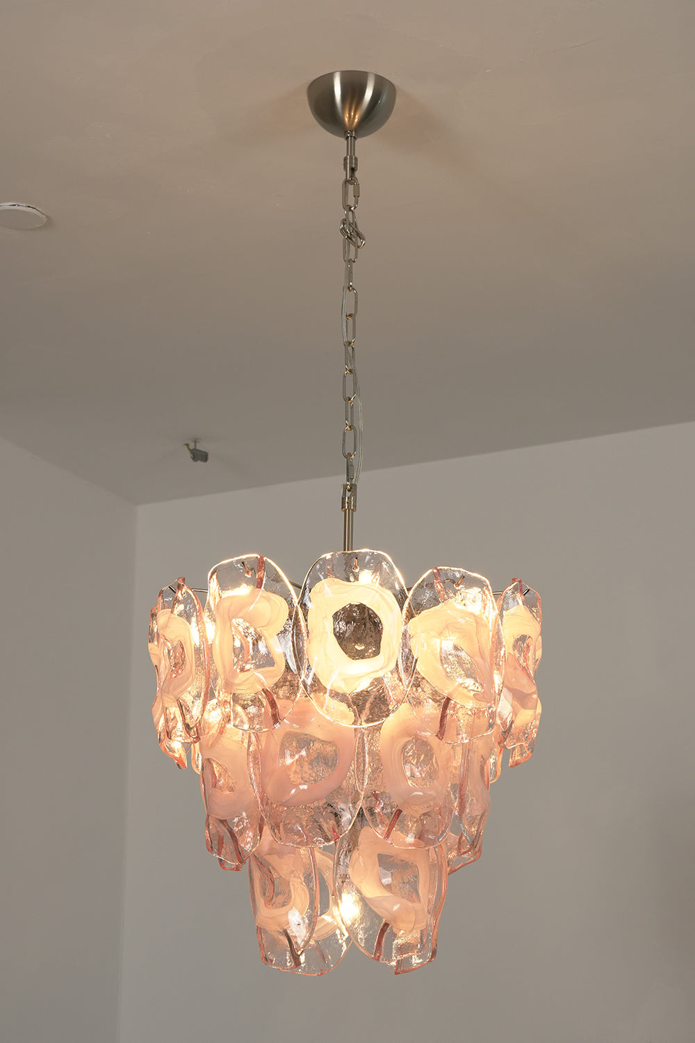 Lit pink glass chandelier | Metal, Glass | Perspective view installed on a white ceiling | vexa lamps