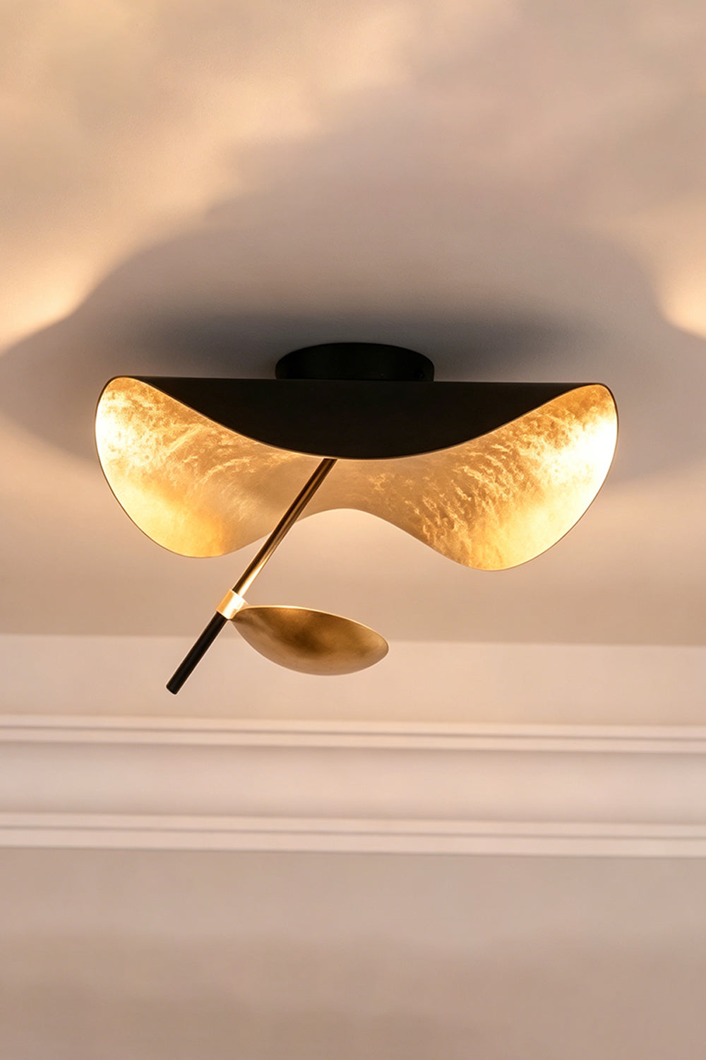 Gold-Tone Sculptural Ceiling Light featuring wave-like design and matte black canopy.