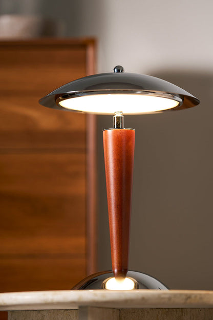 Isolde Domed Walnut Table Lamp | Cozy Accent Glow | Staged view of the fully illuminated mushroom lamp casting a warm yellow halo against a dark blurred wooden chest background | vexa lamps