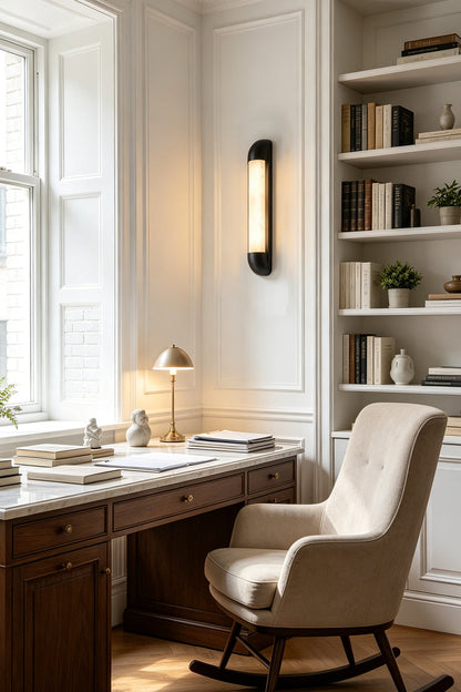 Kester Alabaster Tube Wall Sconce illuminating a stylish home office with a wooden desk and bookshelf.