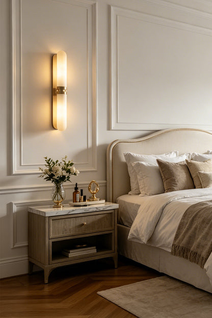Linea Alabaster Capsule Wall Sconce | Alabaster, Brass | Mounted as a cozy bedtime reading light above a wooden nightstand in a serene classical bedroom | vexa lamps
