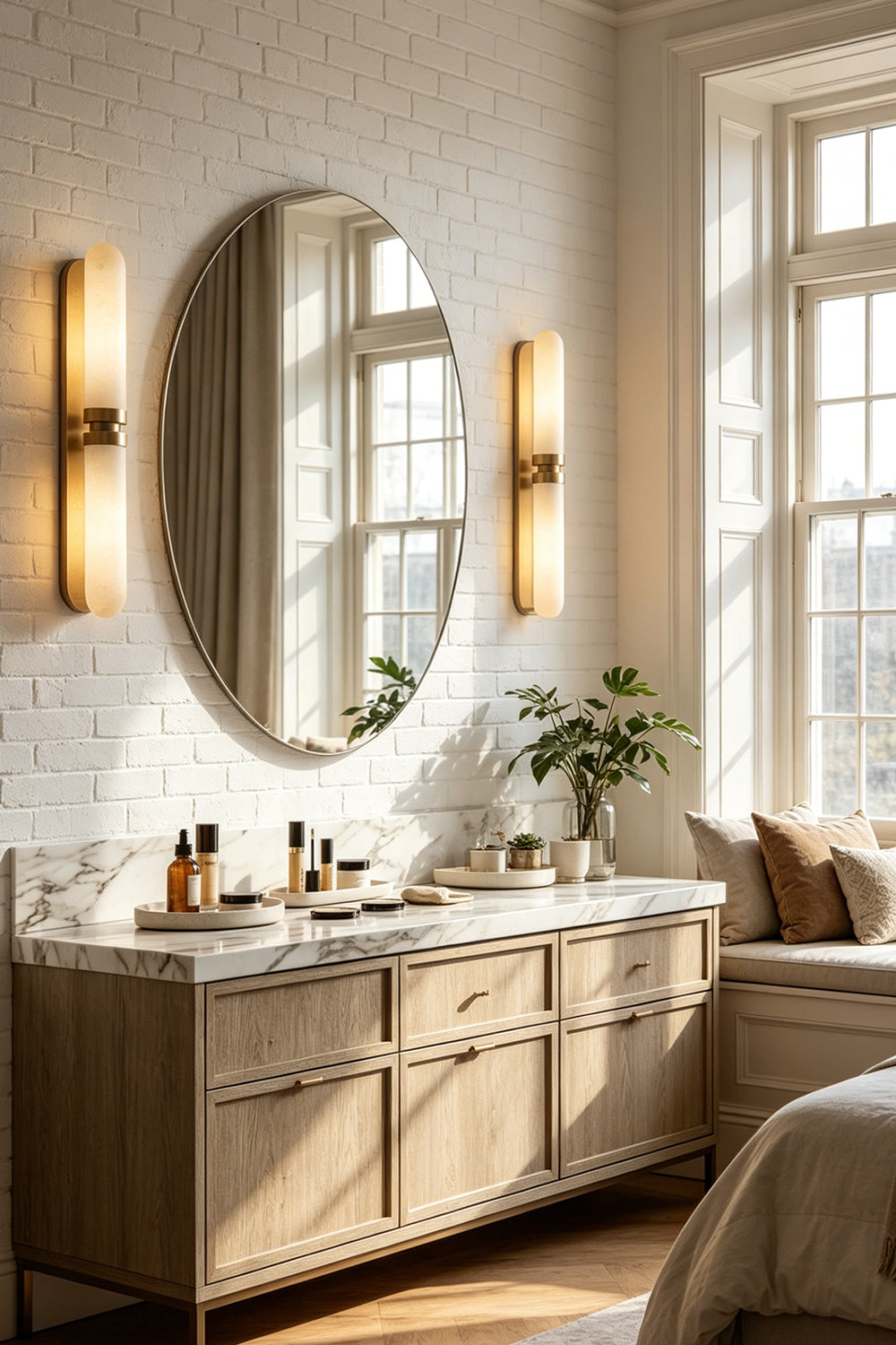 Linea Alabaster Capsule Wall Sconce | Alabaster, Brass | A pair of fully illuminated capsule wall lights flanking a large round mirror in a luxury bathroom vanity setup | vexa lamps