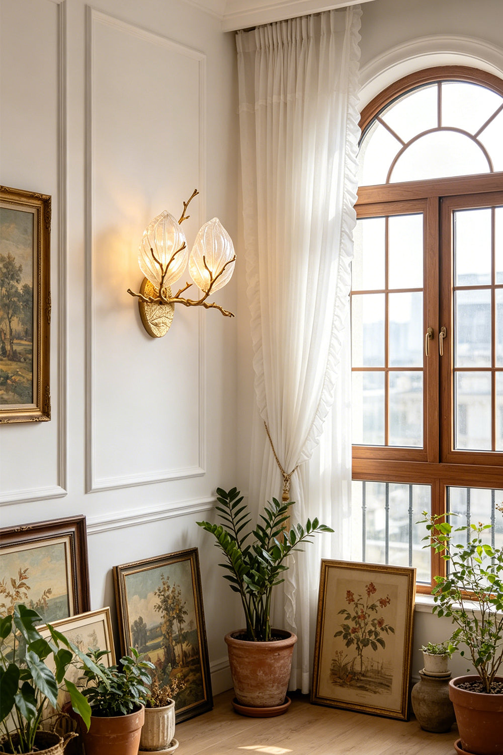 Magnolia Arbor Brass Wall Lamp | Brass, Glass | Illuminating a bright room corner filled with green potted plants and leaning artwork frames | vexa lamps