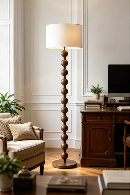 Marlow Stacked Wood Floor Lamp | Wood, Fabric | Positioned as an elegant reading light in a home office or study room near a dark wood desk and upholstered seating | vexa lamps