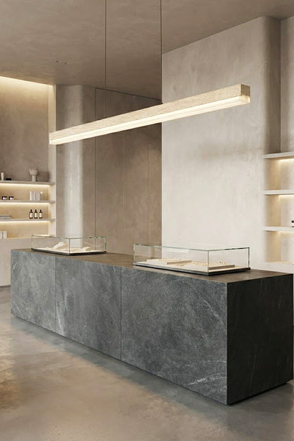 Long travertine linear light over a stone counter | Travertine, Wood, Acrylic | Commercial or gallery interior with minimalist decor | vexa lamps