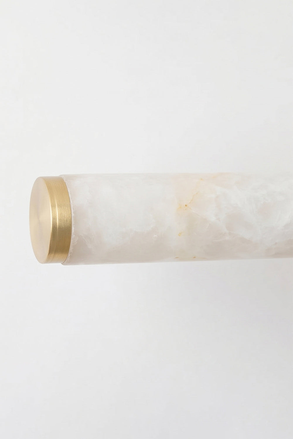 Nerida Linear Alabaster Wall Sconce | Alabaster, Brass | Close-up view focusing on the clean unlit end section of the natural white stone cylinder finished with a brushed gold brass end-cap | Detail shot | vexa lamps