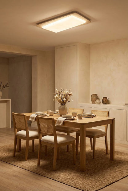 Travertine rectangular light in a dining area | Yellow Travertine, Acrylic | Centered over a wooden dining table with chairs | vexa lamps