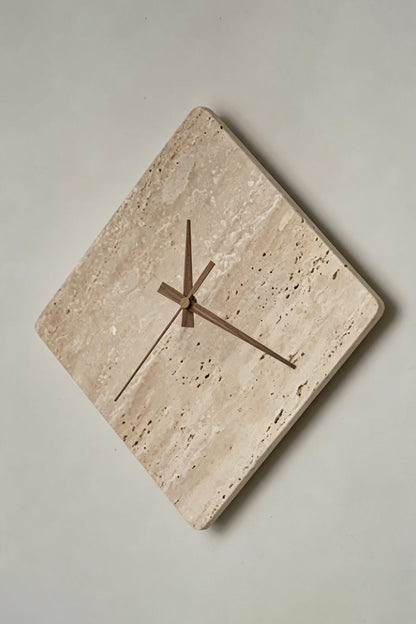 Petra Compass Travertine Backlit Wall Lamp | Travertine, Iron | Angled frontal view of the unlit travertine clock-lamp displaying its natural porous stone surface against a grey wall | Detail shot | vexa lamps