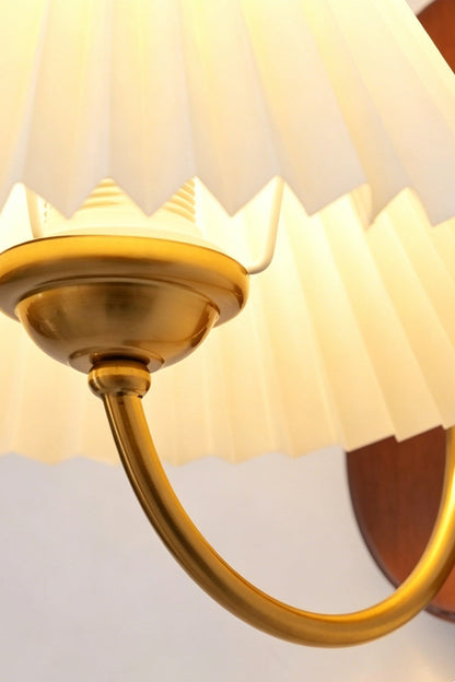 Pleated Fabric Wall Lamp | Fabric, Metal, Wood | Close-up view from underneath focusing on the curved brass support arm and light socket attachment | Detail shot | vexa lamps