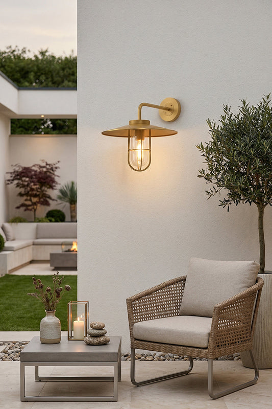 Brass Portree wall lamp installed on an outdoor patio wall | Brass, Glass | Outdoor garden scene with lounge furniture | vexa lamps