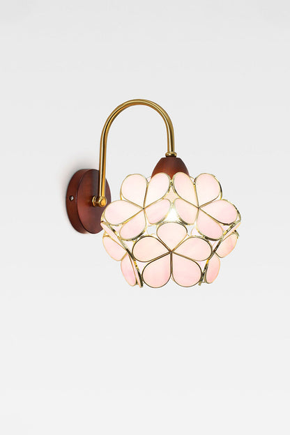 Rosalind Petal Glass Botanical Wall Lamp | Glass, Metal, Wood | Isolated lit product view of the pale pink glass petal variant radiating a warm golden glow on a white background | vexa lamps