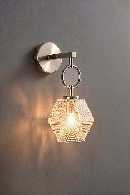 Rosamund Faceted Glass Wall Sconce | Faceted Glass and Silver Metal | Brushed nickel finish version glowing against a dark background | vexa lamps