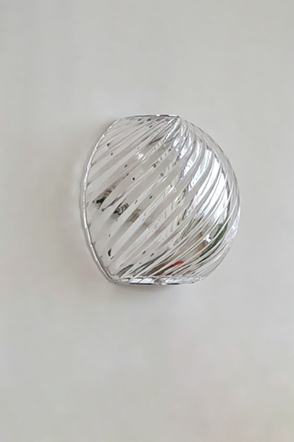 Silas Ribbed Glass Wall Sconce | Ribbed Glass, Metal | Studio unlit view of the clear silver ribbed glass finish variant showcasing its organic pebble silhouette against a plain backdrop | vexa lamps