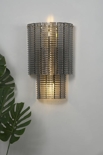 Sovereign Lattice Smoky Glass Wall Lamp illuminating a modern wall with decorative green foliage.