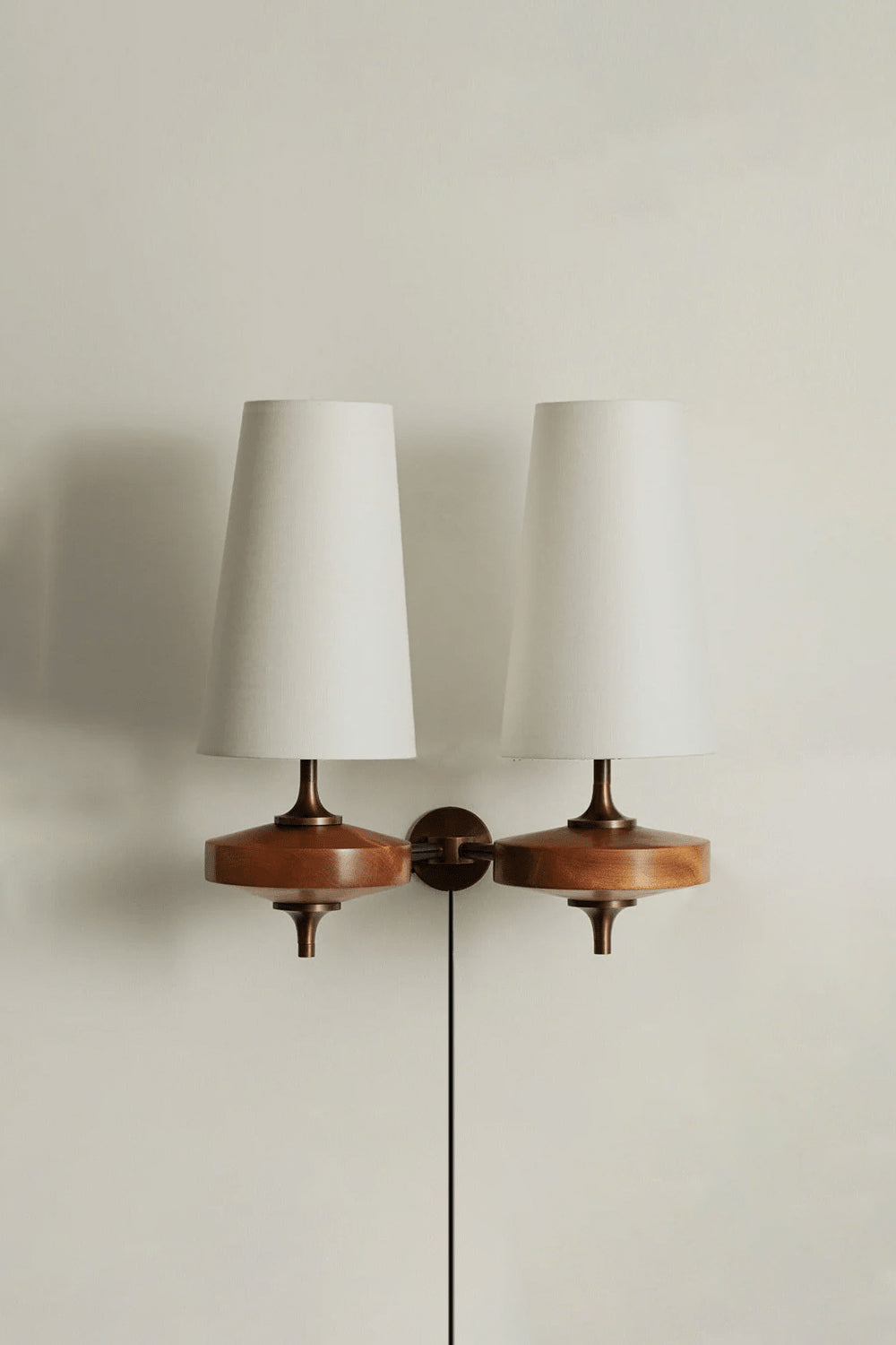 Spindle Walnut Wood Wall Sconce featuring a turned walnut-toned wood base and white fabric shades for warm accent lighting.