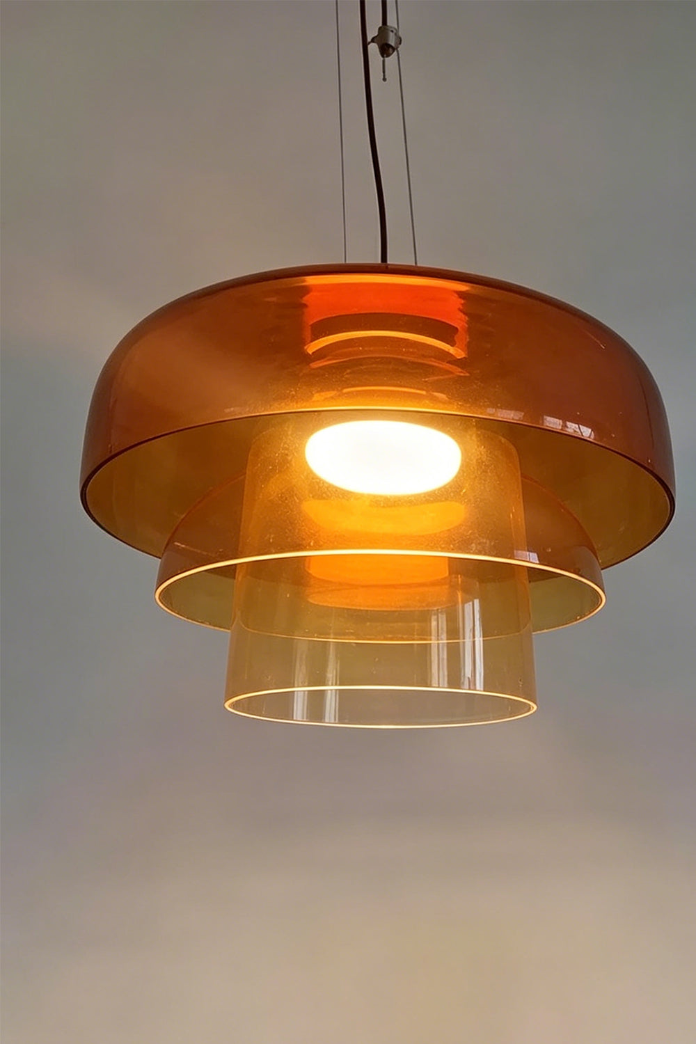 Stratum Layered Glass Pendant Light | Glass, Metal | Detailed frontal view of the illuminated orange glass layers showcasing its warm internal light source | Detail shot | vexa lamps