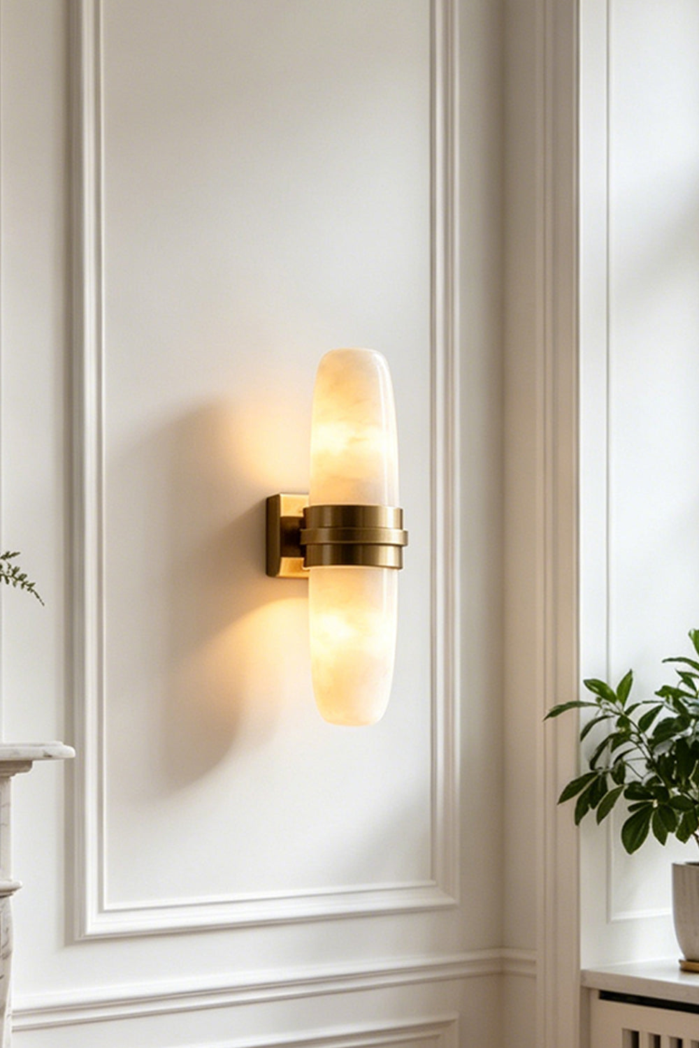 Theron Linear Alabaster Wall Lamp | Alabaster, Metal | Close-up shot of the fully lit capsule lamp casting a warm bi-directional glow on a white decorative wall panel | vexa lamps